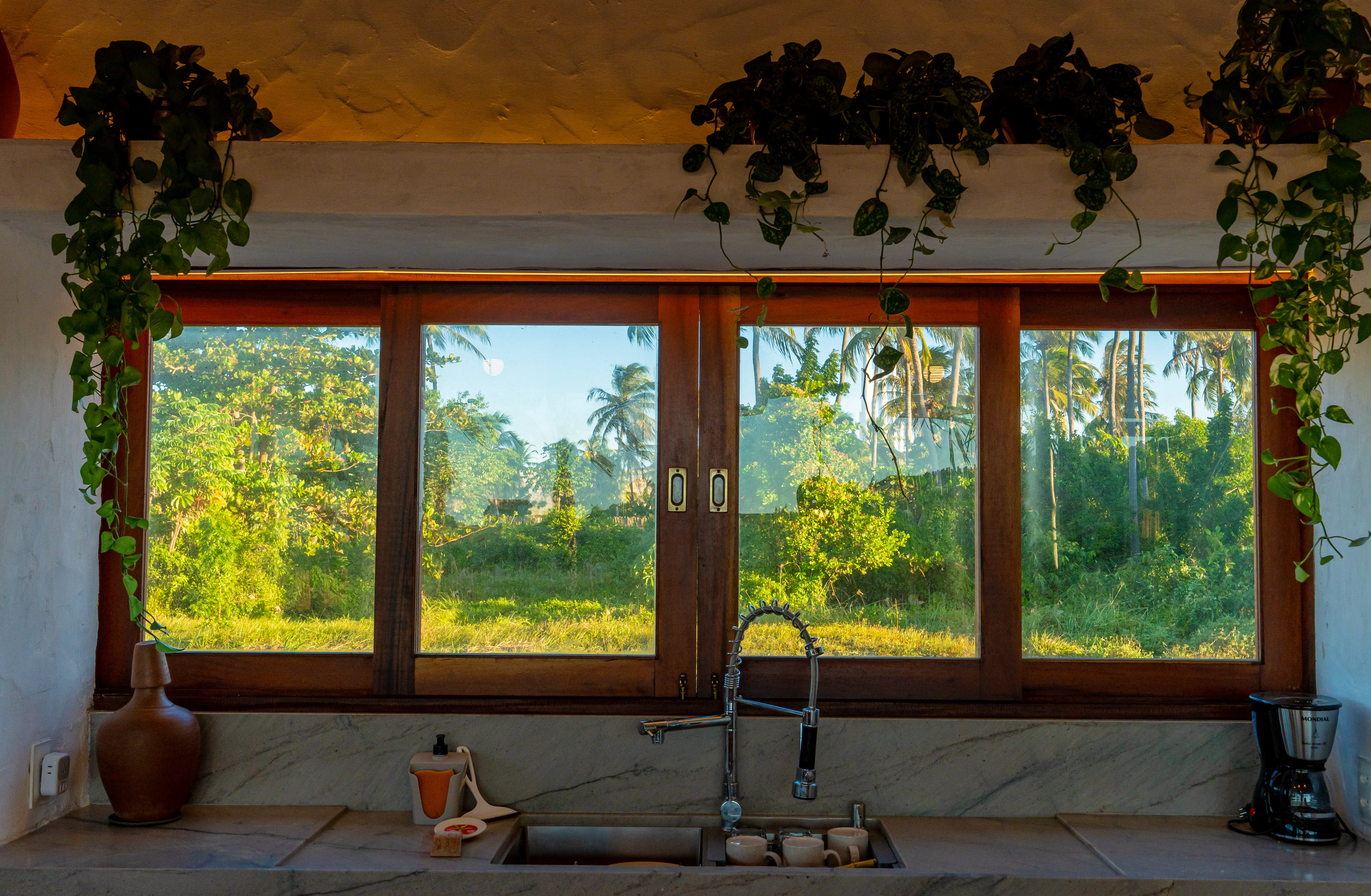 Janela da cozinha da Casa Areia com vegetação ao fundo